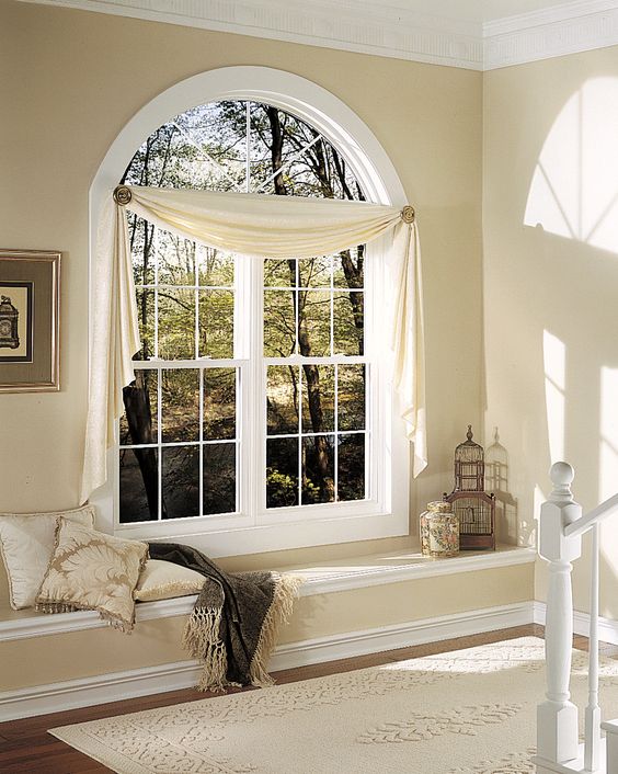 a chic staircase space with an arched window accented with some curtains, lanterns and pillows