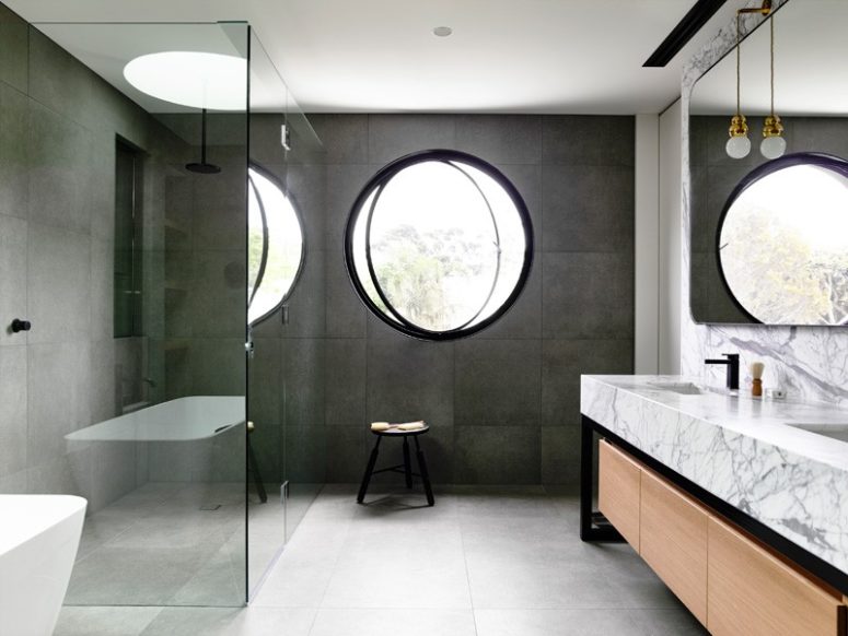 a contemporary bathroom with concrete tiles, a marble vanity, a round pivot window for a modern feel