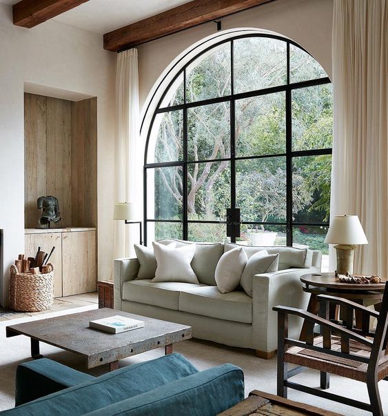 a contemporary living room with an oversized black frame arched window that includes an access to the garden