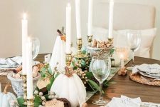a cozy rustic Thanksgiving tablescape with a printed runner, white and light blue pumpkins, tall candles, berries, woven placemats and candles