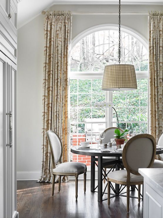 a formal meets farmhouse dining space with a large arched window that brings a lot of natural light inside