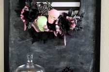 a gorgeous and non-typical striped Halloween wreath with neon skulls, black and pink bows is a cool idea with a slight vintage feel