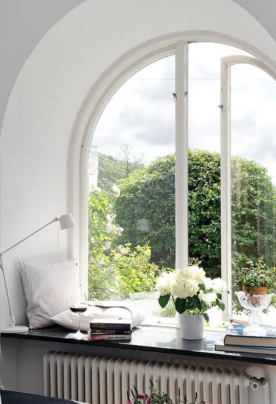 a gorgeous sitting nook - an arched window with a windowsill with pillows, books and wine is a great idea for any space