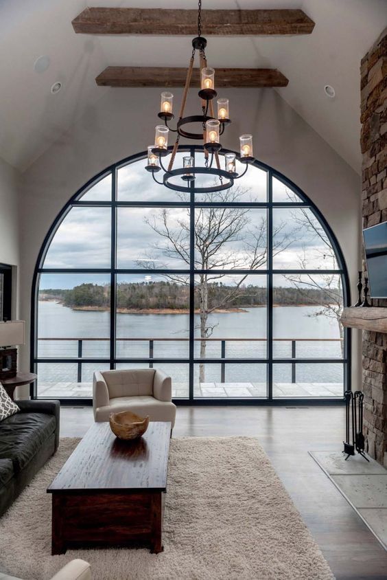 a living room with an oversized arched window that brings a gorgeous view inside