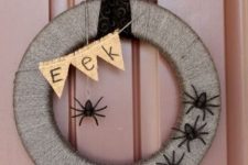 a lovely rustic Halloween wreath wrapped with yarn, with black spiders, a burlap bunting and chic ribbon is amazing