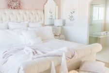a luxurious bedroom with a pink accent wall, a white upholstered bed and white bedding, a pink velvet bench, a fan and neutral lamps