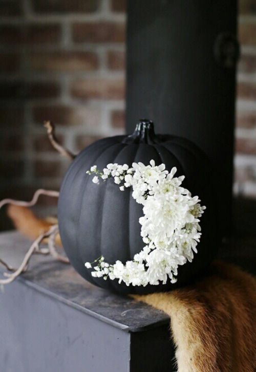 a matte black pumpkin decorated with white flowers as a moon is a beautiful Halloween decoration