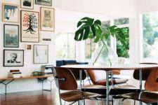a mid-century modern dining space with a bright gallery wall, a plywood table and chairs, a glazed wall and clerestory windows for more light