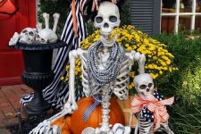 a mini fun skeleton scene with a skeleton girl and a baby dressed up in jewelry and bold fabric bows is a cool idea for Halloween