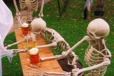 a mini outdoor Halloween scene with skeletons drinking beer is a fun idea for those who enjoy drinking it too