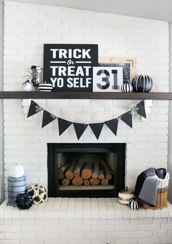 a modern Halloween fireplace clad with white brick, with black signs and artworks, black and white pumpkins and spiders is very stylish