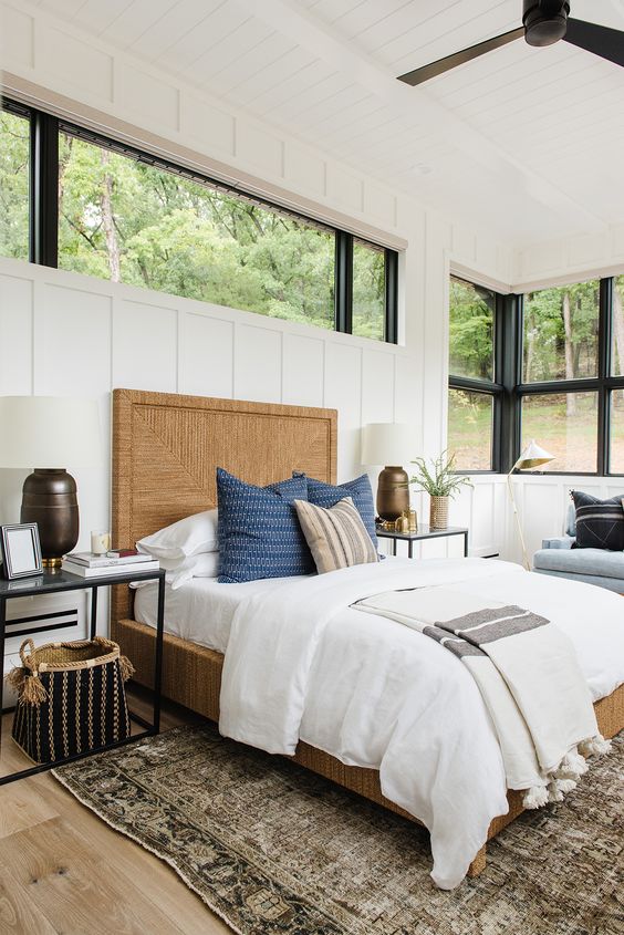 a modern farmhouse bedroom with a blue bench with pillows, a large window and an additional clerestory one