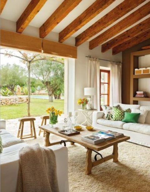a modern farmhouse living room with wooden beams, neutral seating furniture, a wooden coffee table and colorful pillows
