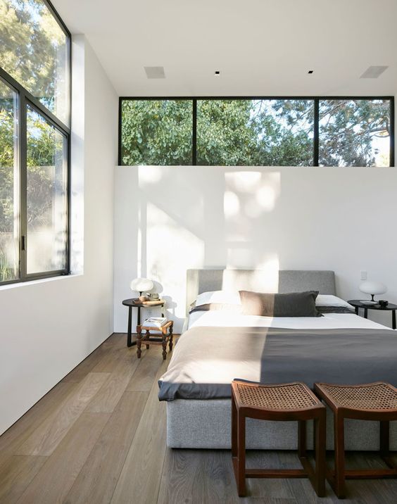 a modern neutral bedroom with contemporary furniture, a large window and a clerestory window over the bed is super chic