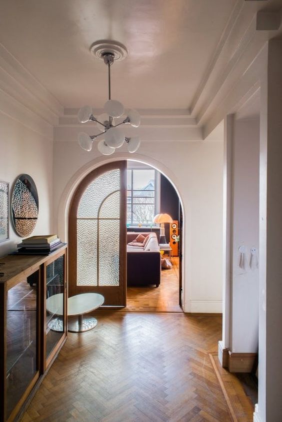 a modern space with large arched doors with frosted glass that highlight the style and match the floors with their stain