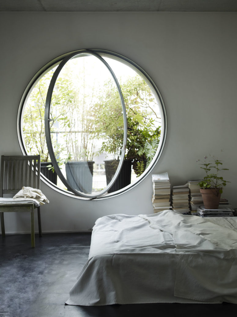 a neutral and airy bedroom done with a round pivot window, which allows fresh air in easily and brings much light