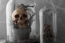 a planter with a skull and a bird, a faux owl placed into cloches for moody and chic Halloween decor that wows