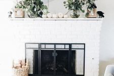 a pretty farmhouse mantel with white pumpkins, eucalyptus in vases, wooden candleholders and a blackbird is cool and fresh