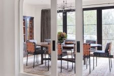 a pretty modern dining space with a glazed wall, an oval table and black chairs plus white arched glass pocket doors