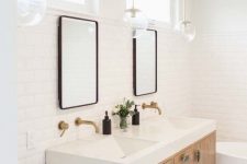 a pretty neutral bathroom with a black and white floor, a light-stained vanity, an oval bathtub, two mirrors and pendant lamps