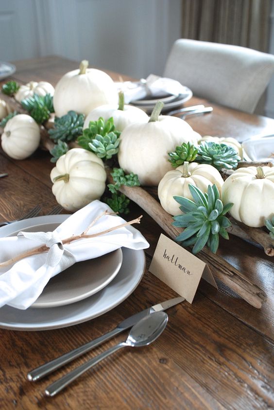 a relaxed rustic Thanksgiving table setting with branches, succulents, white pumpkins, neutral napkins and twigs on each place setting