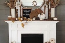 a relaxed rustic fall fireplace with wooden cutting boards, leaves, vine and faux pumpkins, wooden candlesticks and a sign