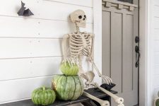 a rustic Halloween porch with heirloom pumpkins, a skeleton and some bats on the wall is a cool idea