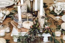 a rustic Thanksgiving tablescape with wooden boards, candles, greenery and berries, white pumpkins and candles is cool