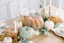 a rustic boho Thanksgiving tablescape with a macrame runner, heirloom pumpkins, candles and striped napkins