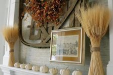 a rustic fall mantel with pumpkins, wheat, a faux berry and leaf wreath and a giant woven basket is a bold idea to style your mantel