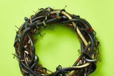 a scary Halloween wreath of vine interwoven with black and green faux snakes is a spooky and a veyr realistic decoration
