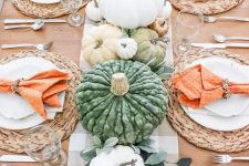 a simple and cozy bright Thanksgiving tablescape with a plaid runner, orange napkins, heirloom pumpkins, greenery and woven placemats