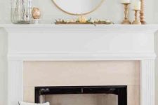 a simple and lovely rustic mantel with faux pumpkins and greenery, bold dried leaves, pillar candles in wooden candleholders
