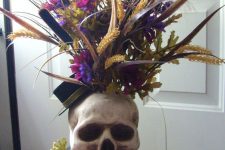 a skull vase with bold blooms, grasses and bright faux flowers is a lovely idea for Halloween, it can be used as a centerpiece