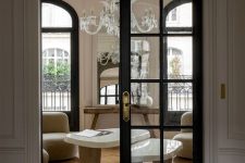 a sophisticated French chic space with black frame French arched doors leading to it, these doors highlight the sophistication of the style