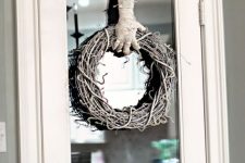 a spooky and cool Halloween wreath of vine holded by a mummy hand is a very fresh and catchy piece to make yourself