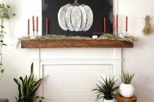 a stylish rustic fall mantel with grass, bold orange candles, a chalkboard pumpkin is a laconic and delicate decor idea
