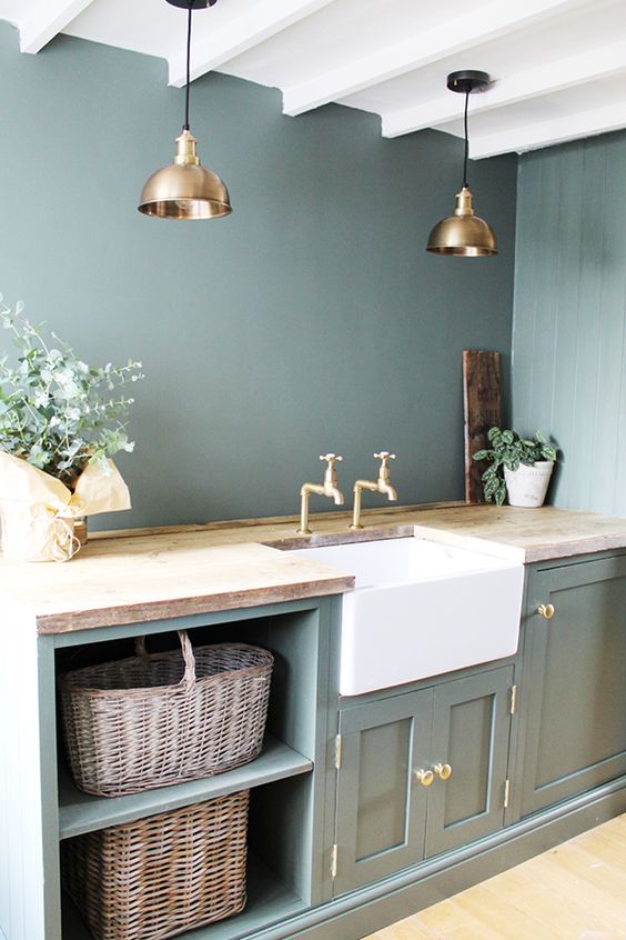 a vintage green kitchen with butcherblock countertops, brass pendant lamps and knobs plus baskets for storage is amazing
