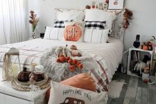 a whimsy fall bedroom with a shabby chic bed, a white bench with storage, pillows and lights, a tassel garland, plaid pillows and blankets, pumpkins and candles