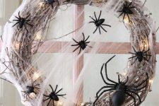 a whitewashed vine Halloween wreath with lights and spiders plus a black and white striped ribbon is a fresh take on classics