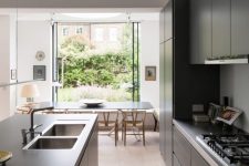 an eclectic space with black sleek furniture, light-stained chairs, a bright rug, glass doors opened to the garden and a clerestory window for more light in the kitchen