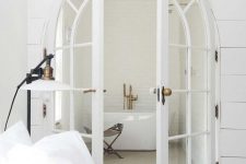 arched white French doors separating an all-white bedroom and its small en-suite bathroom look gorgeous and beautiful