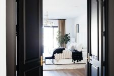 black arched doors leading to a refined modern bedroom with black touches, too, for a chic and bold look
