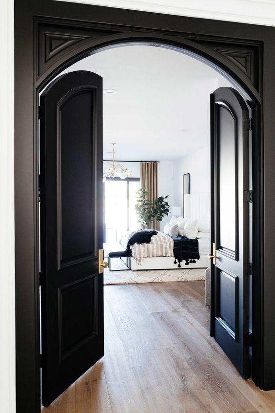 black arched doors leading to a refined modern bedroom with black touches, too, for a chic and bold look
