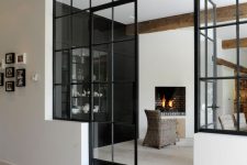 black framed French doors paired with matching windows for connecting the spaces with each other and providing both of them with natural light