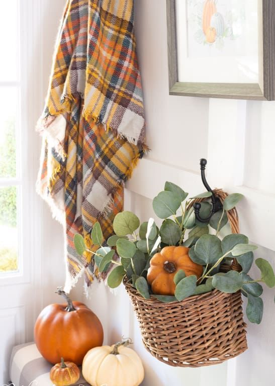 bright faux pumpkins, a pumpkin and greenery in a basket, a plaid blanket will easily cozy up your bathroom for the fall