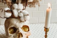 delicate Halloween decor with a neutral and gold skull vase, cotton branches, grasses and candles is a gorgeous idea