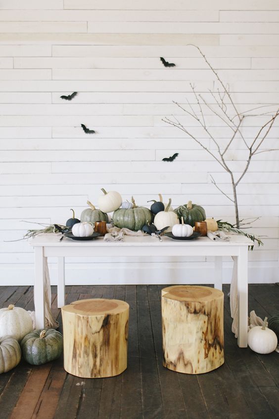 modern farmhouse Halloween decor with pumpkins on the table, tree stumps, branches, black bats and pumpkins on the floor