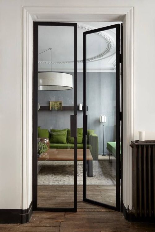 narrow black frame glass doors separate the spaces delicately and highlight the modern style of the apartment
