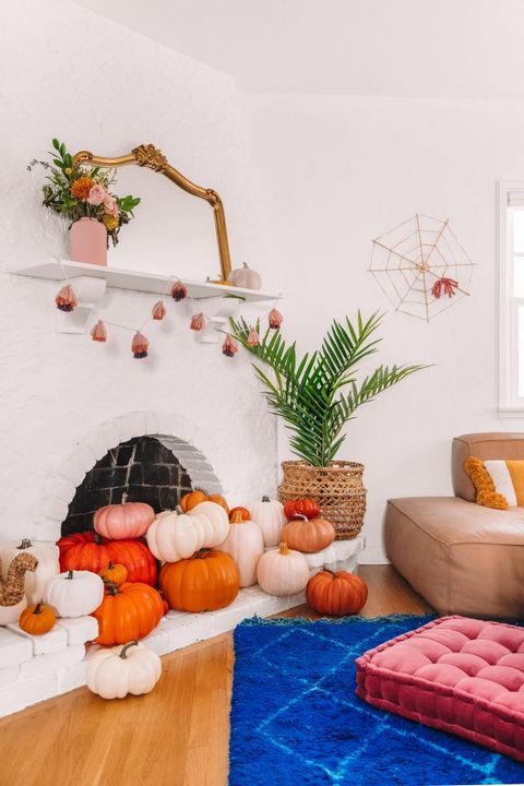 pink, red and orange pumpkins in the fireplace and around it and a mini pumpkin garland plus a spiderweb for modern Halloween decor